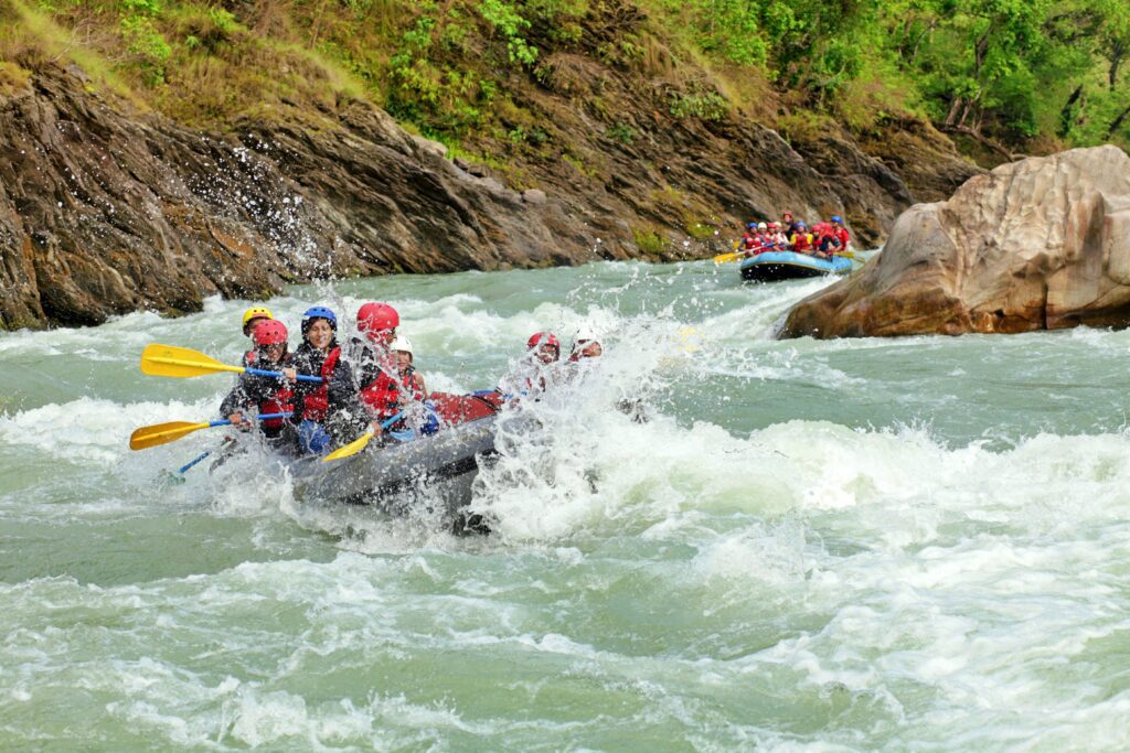 A group of adventurers whitewater rafting on a turbulent river in Nepal, surrounded by rocky cliffs and lush greenery, showcasing the thrill of one of the best trekking destinations.