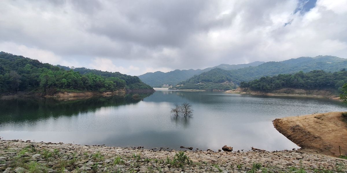 Dhap Dam reservoir surrounded by green hills
