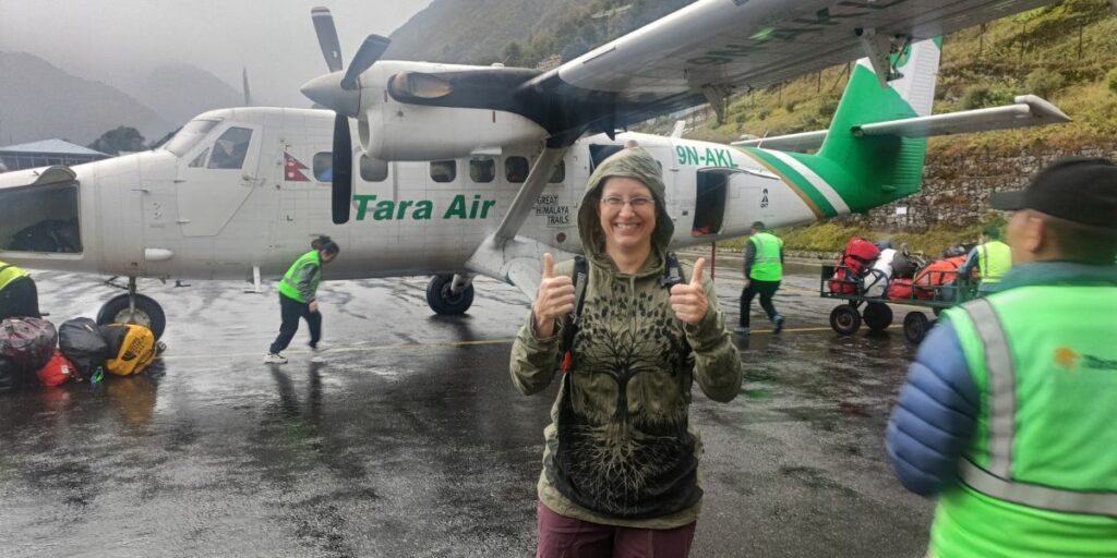 Travelers boarding Tara Air plane in rain at Lukla Airport