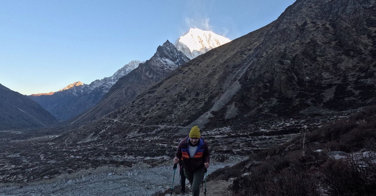 Hiker ascending Langtang trek with sunrise on peaks