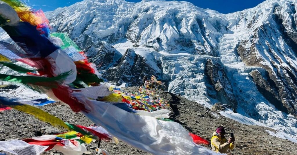 Prayer flags fluttering against the snowy backdrop of Thorong La Pass