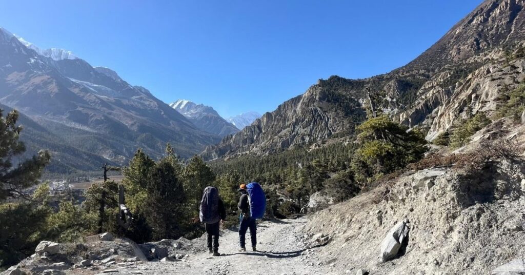 Two trekkers on a high-altitude trail with panoramic mountain views en route to Manang Village
