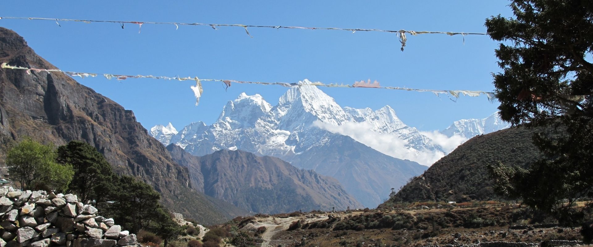 Autumn trail with prayer flags and snowy Himalayan peaks on the Everest Base Camp trek