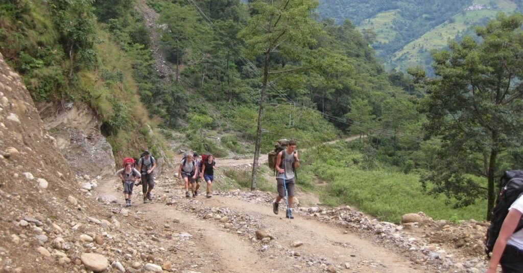 Group joining trek with guides on rocky trail in Nepal hills