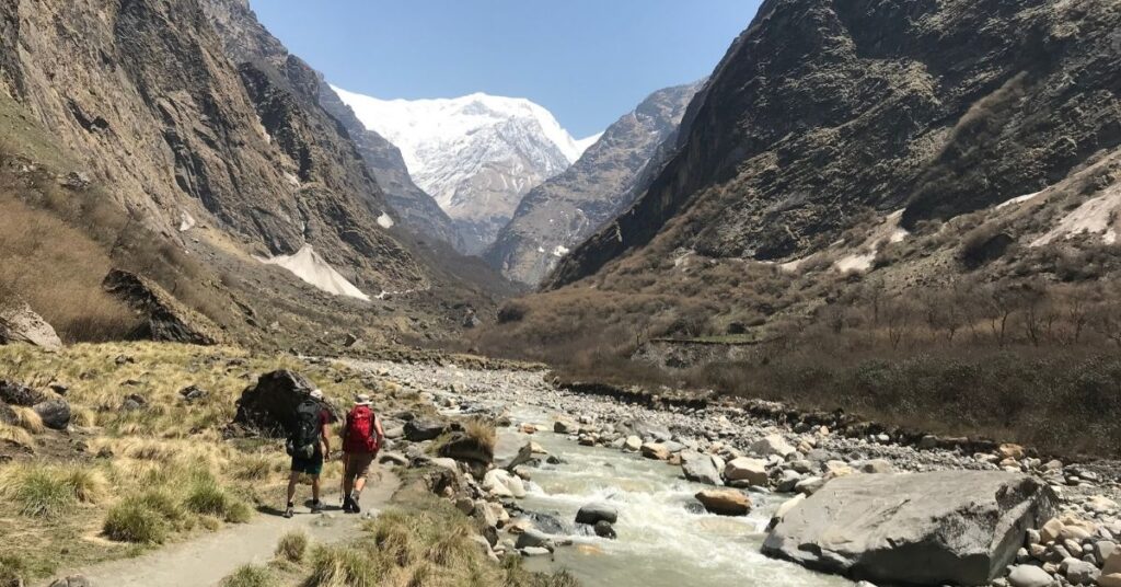 Hikers walking along a river trail toward Annapurna Base Camp with a trek leader