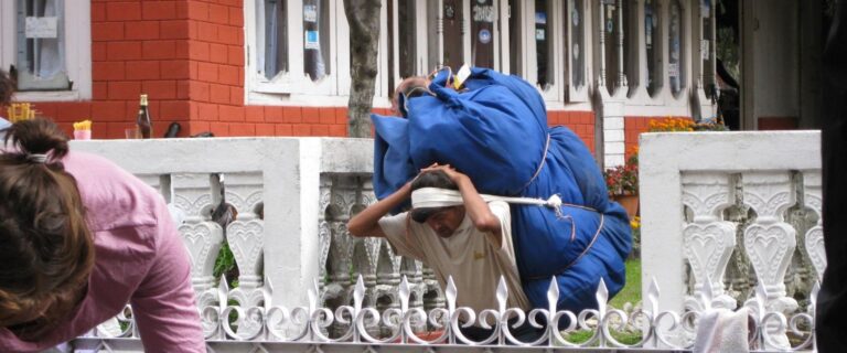 Strong porter supporting trekkers on mountain trail