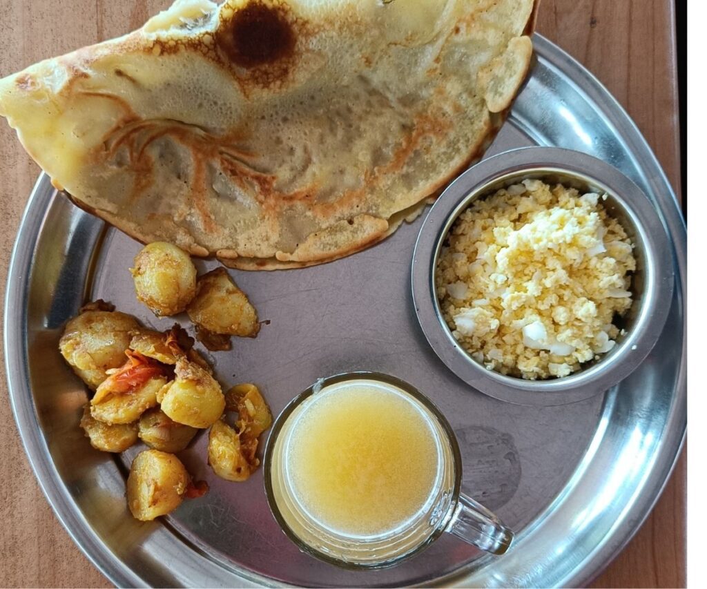 Traditional Nepali trekking breakfast with chapati, fried potatoes, scrambled eggs, and a glass of juice