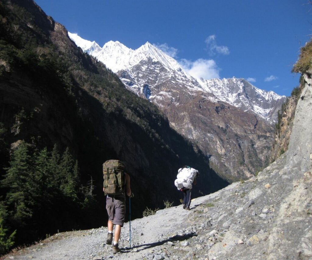 Trekker and porter climbing rocky Manaslu trail