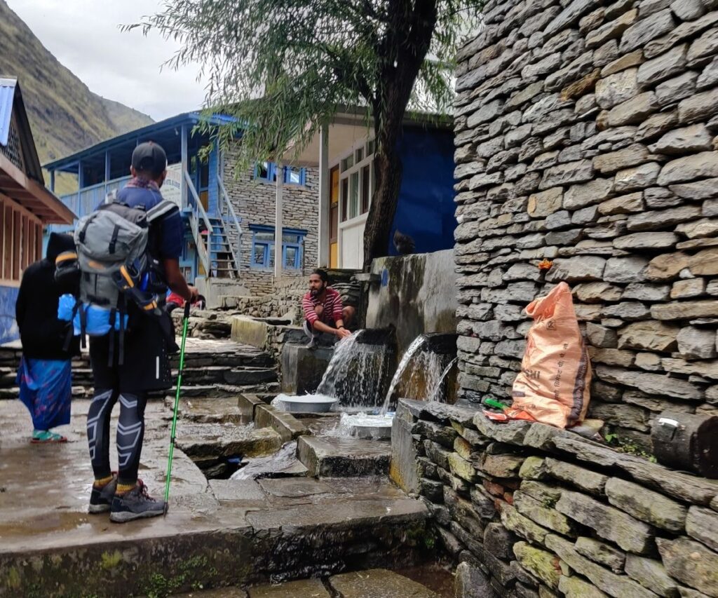 Trekker stops at a low-altitude resting spot with water taps on the Manaslu Circuit Trek