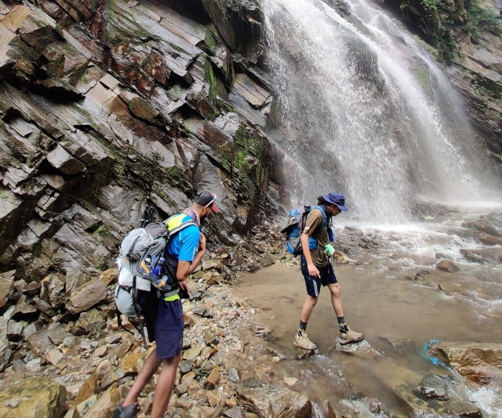 Trekkers carefully walking across wet terrain on Manaslu trail