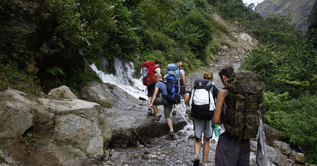 Trekkers crossing a rocky stream near Chame on the Annapurna Circuit trail