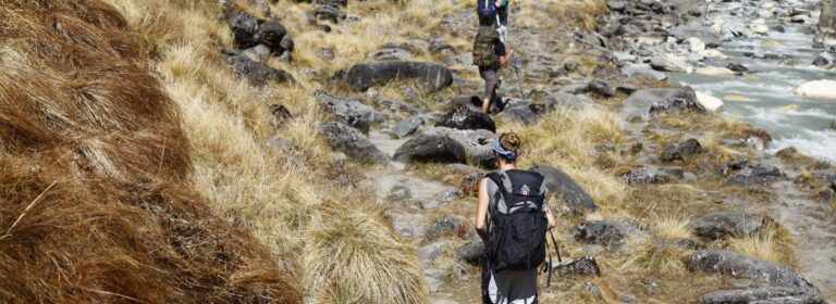 Backpackers following a narrow riverside trail in Nepal