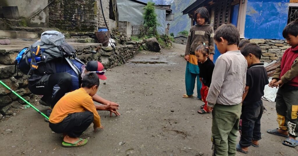 Local children playing games in a mountain village with trekkers