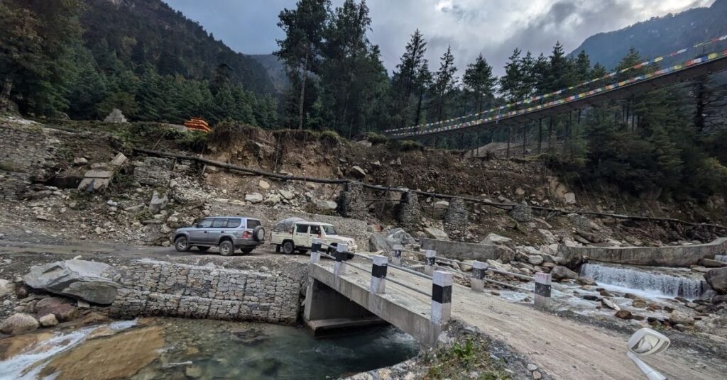 Off-road vehicles set for travel near a mountain bridge in Nepal