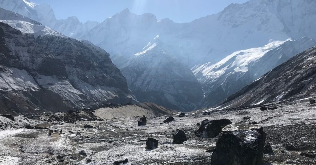 Sunlit Annapurna range shining above trekkers walking across the snowy highland path