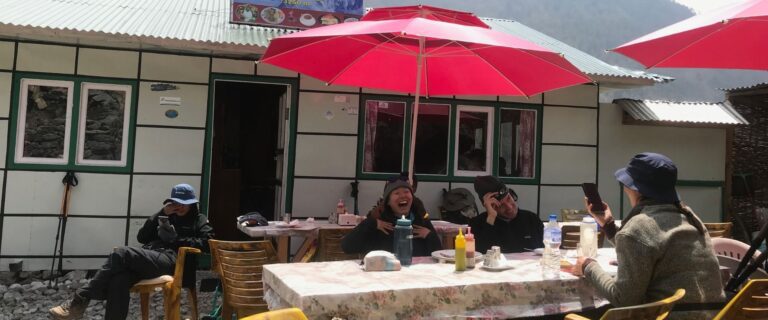 Trekking group enjoying lunch at Everest Summit Lodge with colorful umbrellas and mountain views