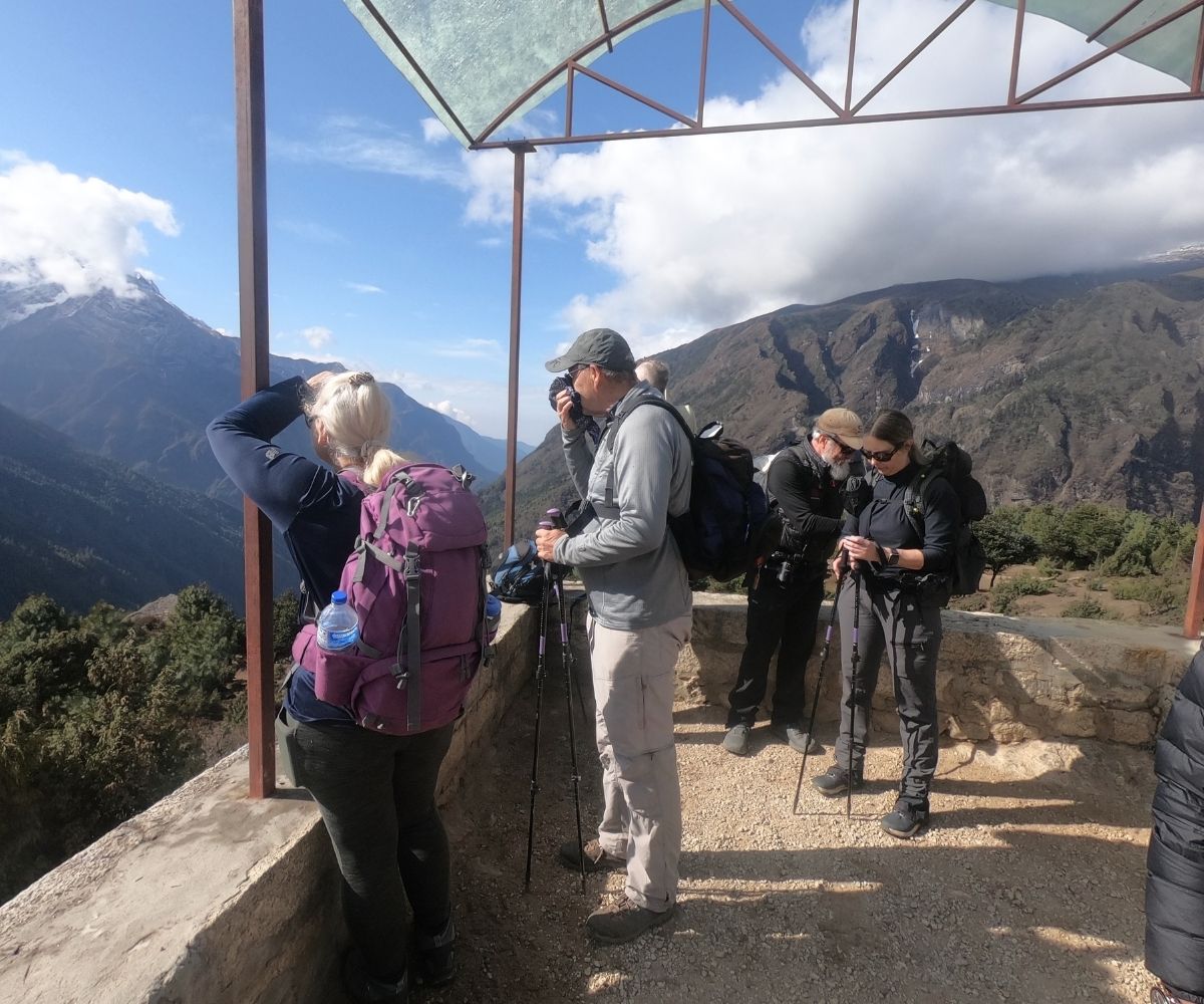Trekking group takes a break on Everest Base Camp trail, checking backpacks and trekking poles
