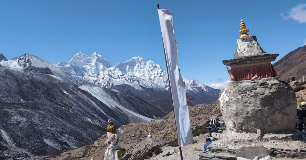 Trekking past stone chortens and prayer flags with clear views of Everest
