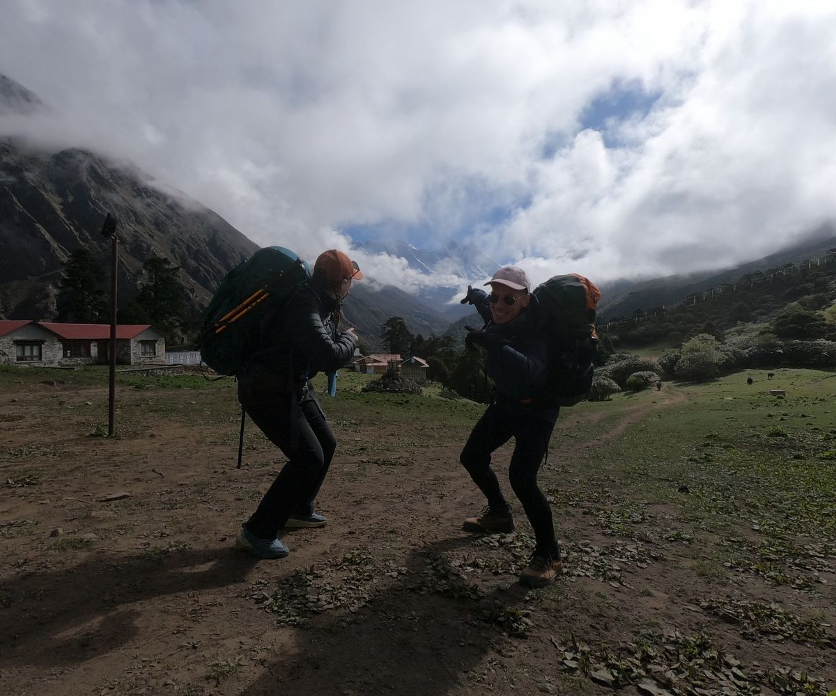 Trekkers playfully posing with backpacks on open trail near Pangboche