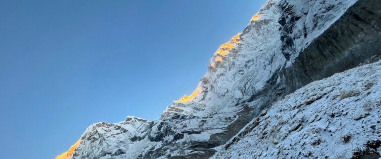Golden sunrise lighting snowy Annapurna peaks at ABC